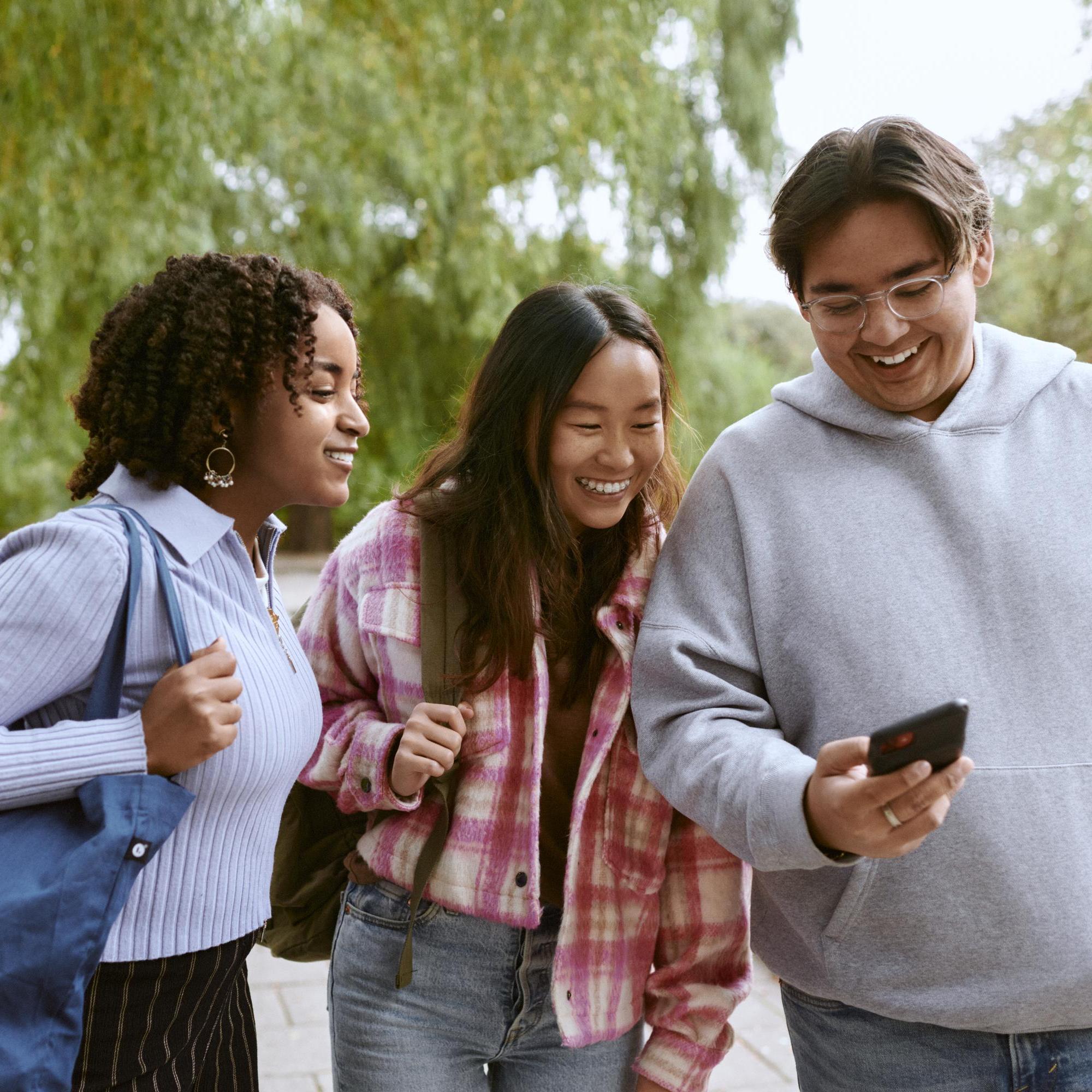Glada studenter tittar på en mobil utomhus